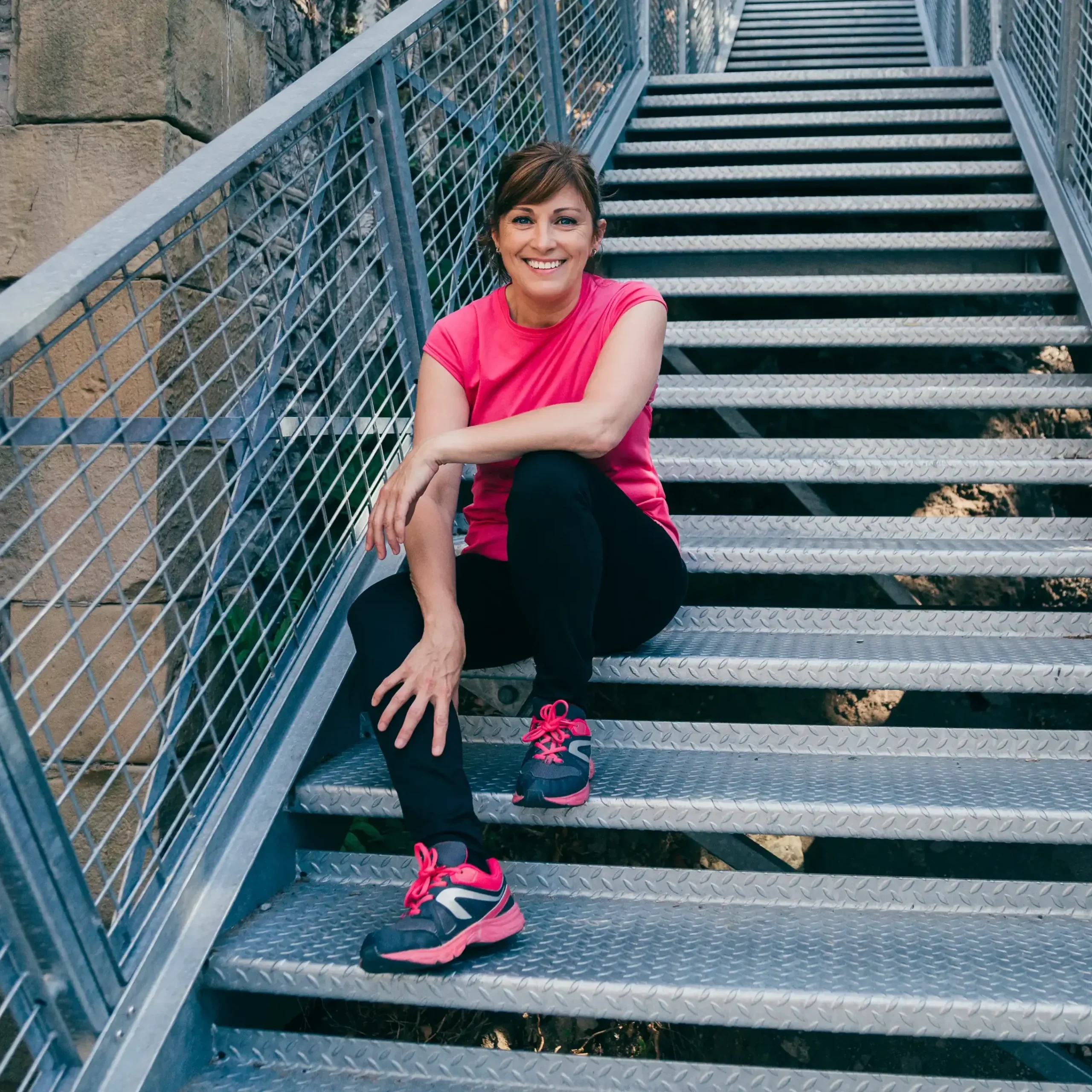 smiling athlete resting on some stairs after exercising