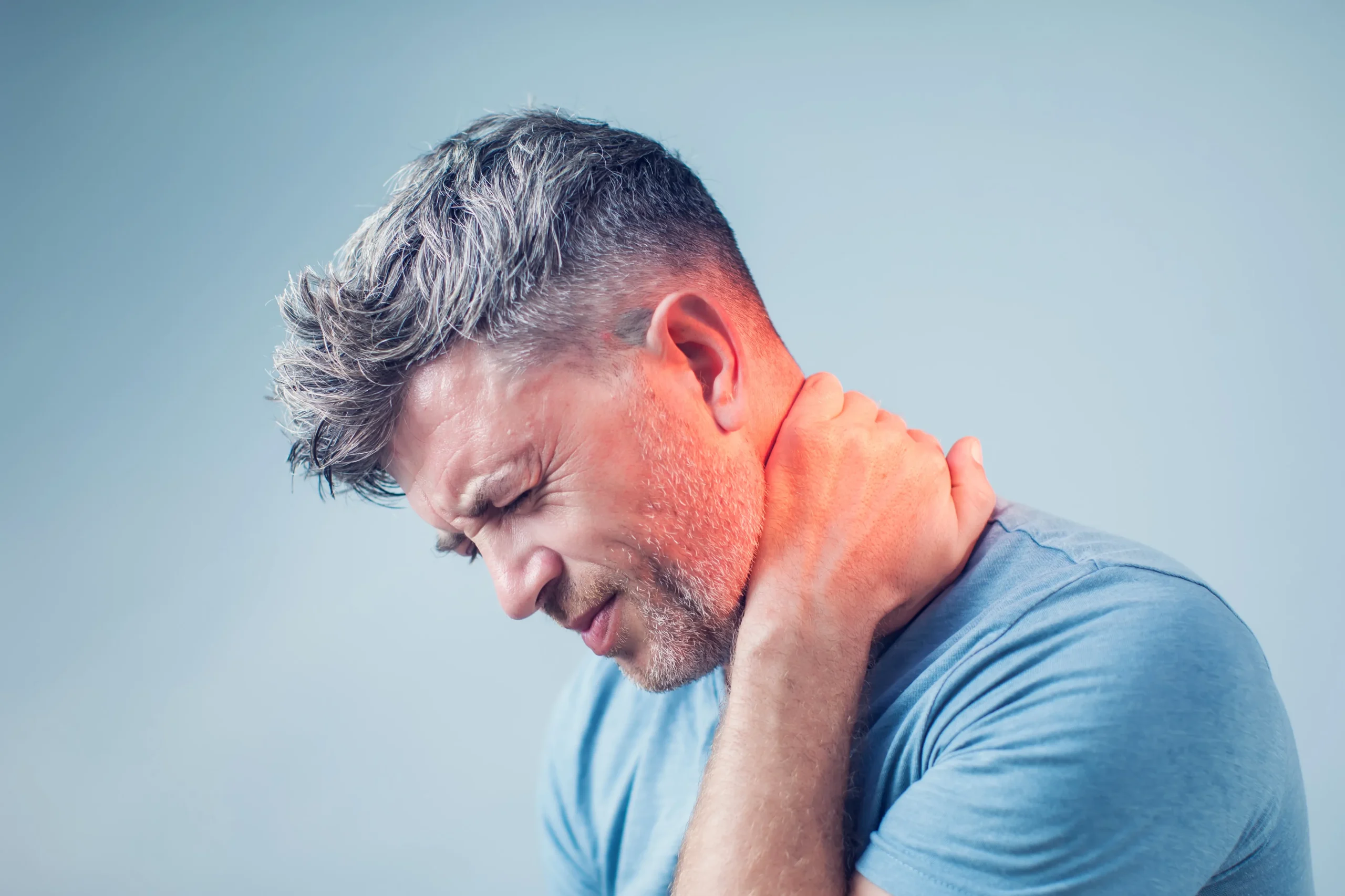 man with neck pain holding the back of his neck