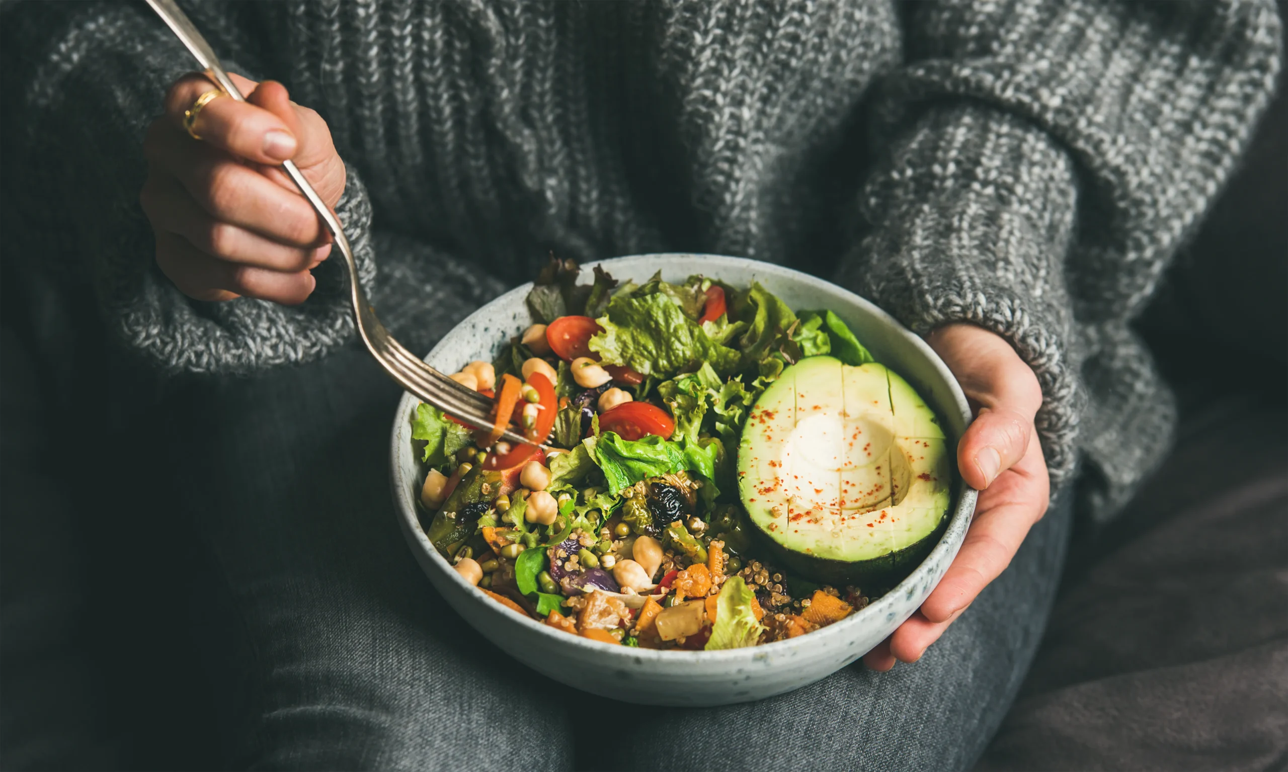 a women holding a plate of a lucky green power bowl filled with vegetables and chickpeas
